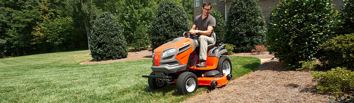 Man riding an orange 2017 Husqvarna LGT2654 riding lawn mower